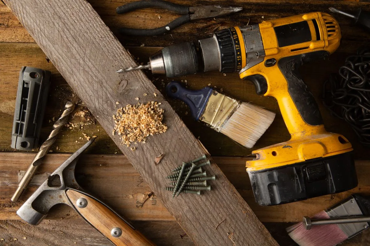 Cordless drill and hand tools on a wooden workbench